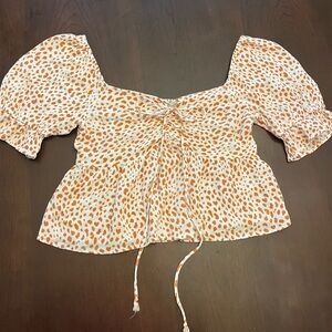 Orange and white Urban Romantics flowy top with tie in front.